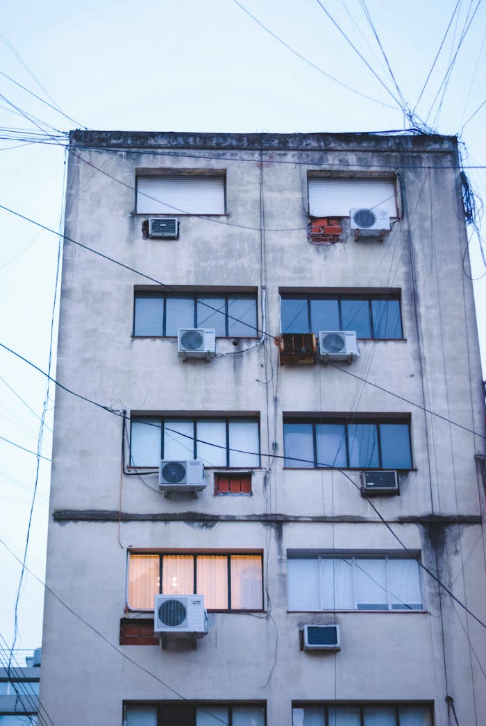 A weathered apartment building in Buenos Aires with multiple air conditioners.