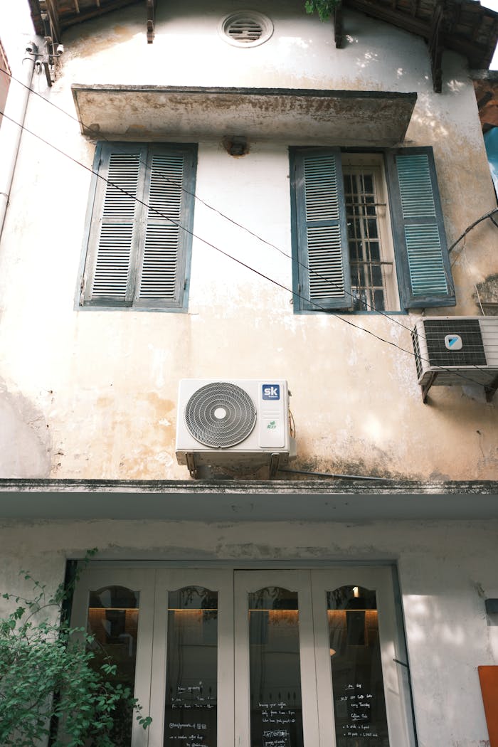 Vintage Jaipur building facade featuring old windows and modern air conditioners.