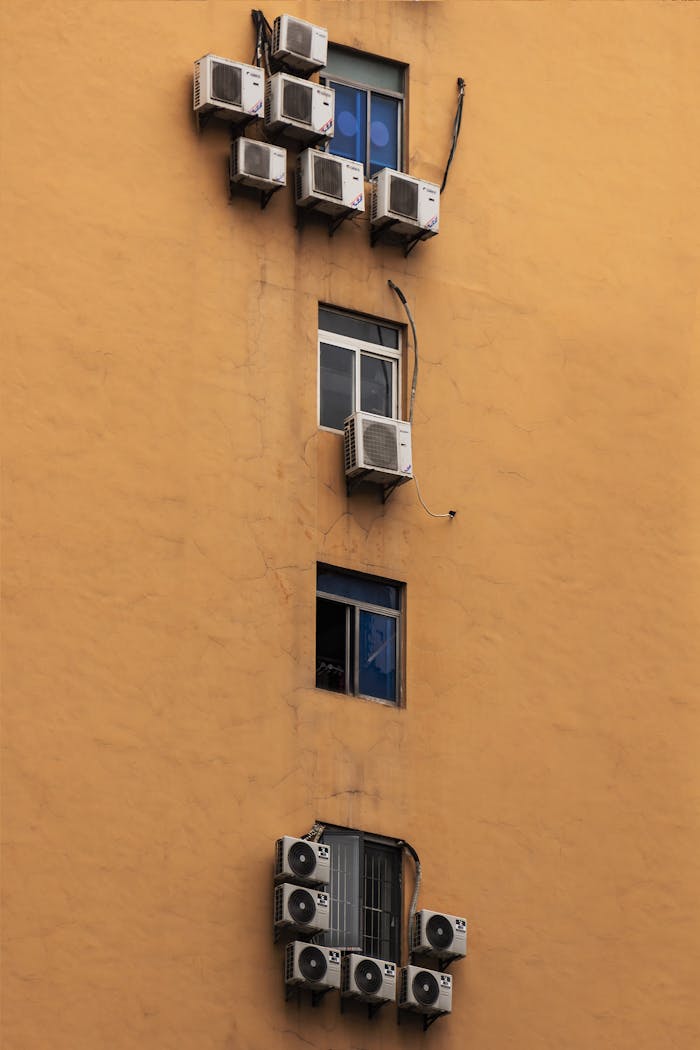 Facade of a building with numerous air conditioners installed on apartment windows.